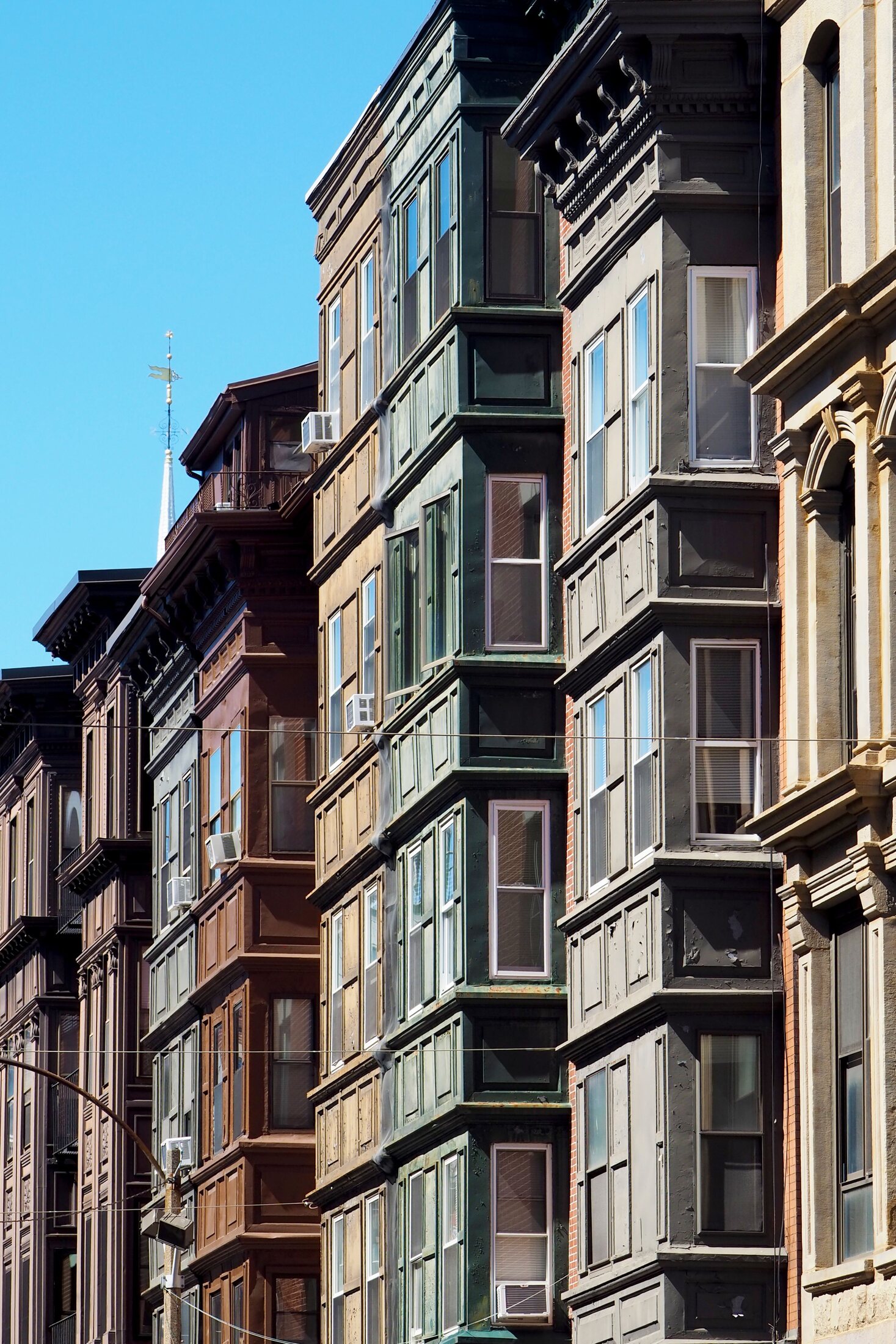A richly detailed row of historic Boston brownstones beneath a clear blue sky