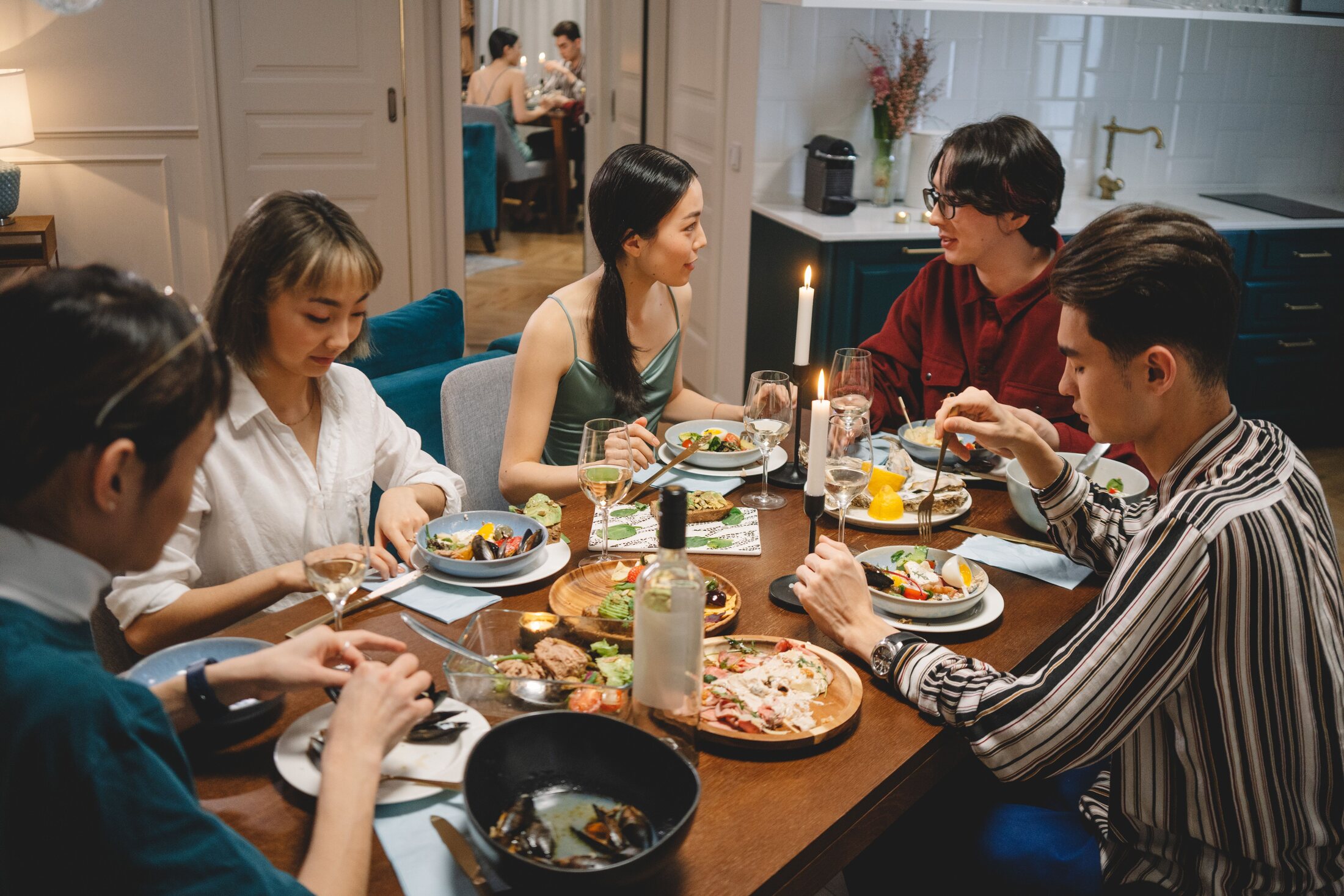 A diverse group of young friends sharing a candlelit dinner in an elegant home