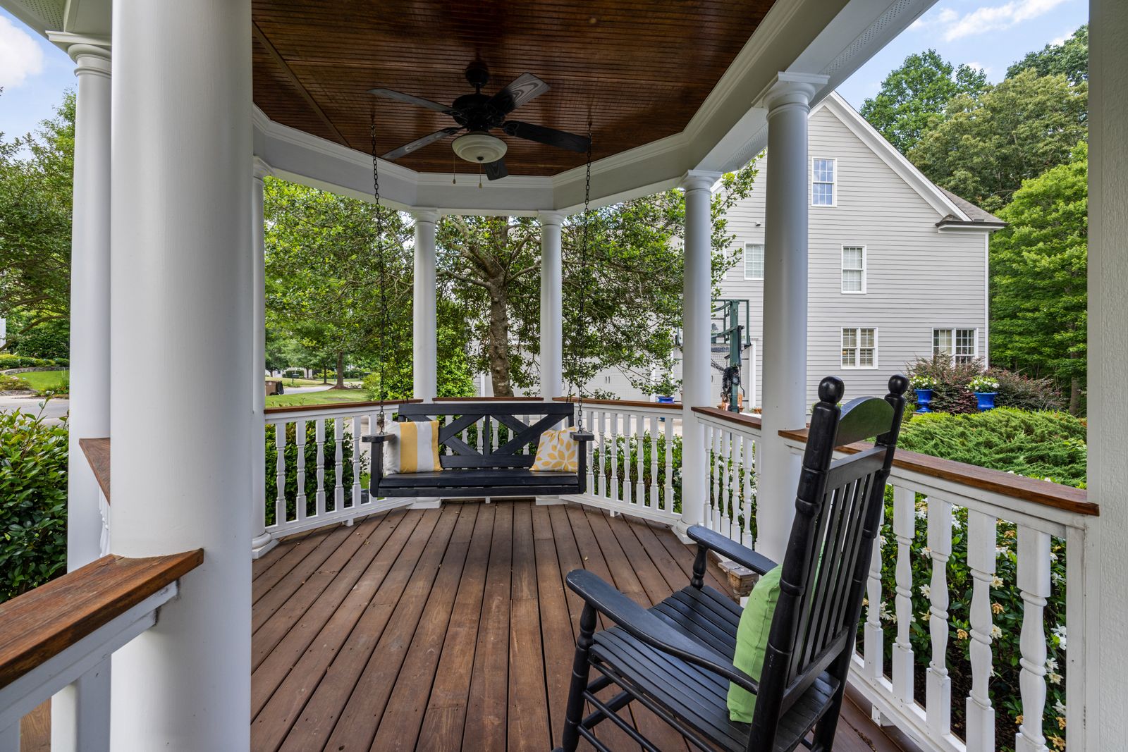 A gracious covered porch with wood floors, rocking chairs, and a porch swing